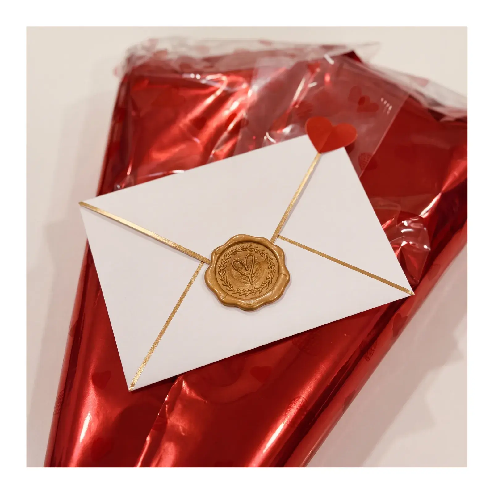 Sobre premium cerrado con lacre dorado sobre el envoltorio rojo